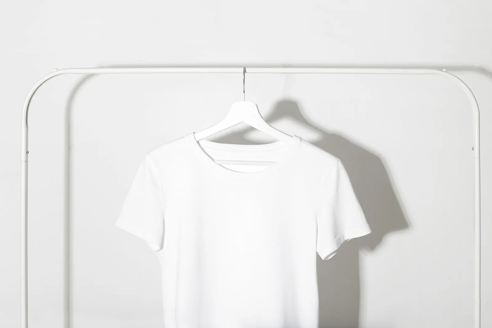 A plain white T-shirt on a hanger against a white background.