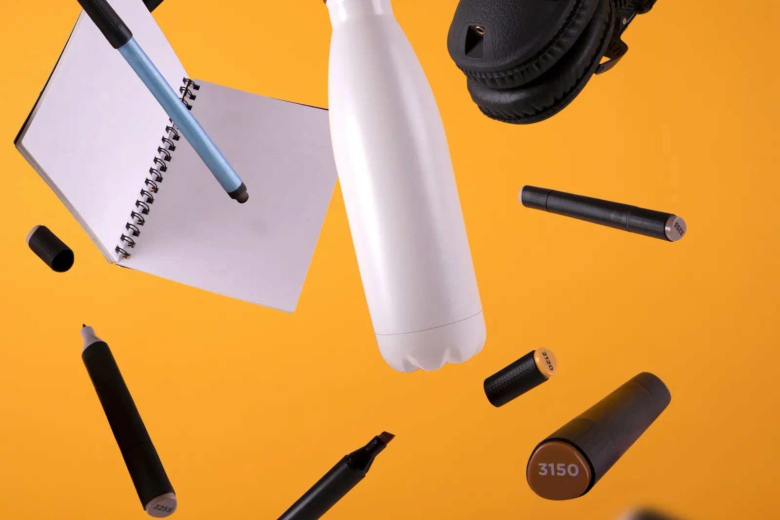 A reusable bottle, notebook, pens and headphones arranged as practical gift options.